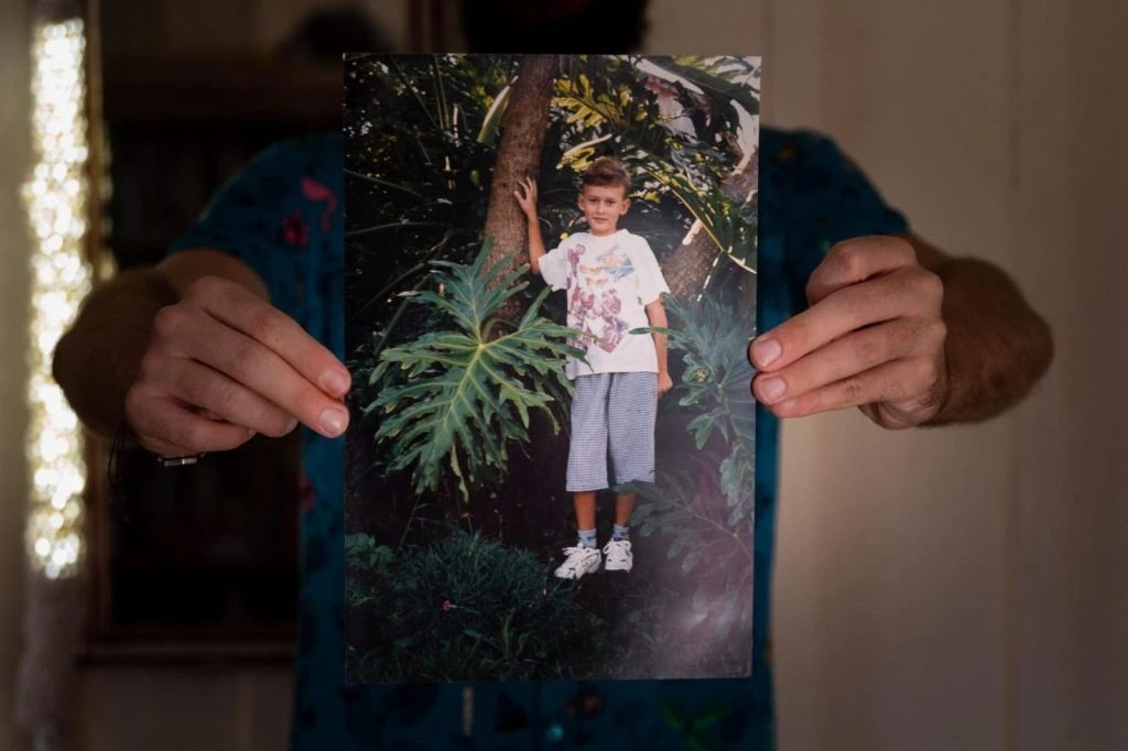 Mãos seguram uma antiga fotografia do menino — memória e arquivo pessoal
