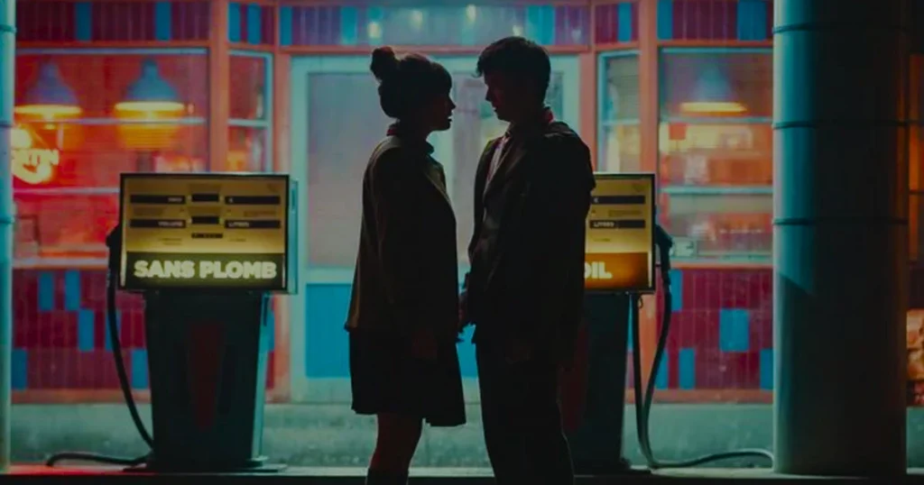 Um casal jovem em silhueta, frente a frente, num posto de gasolina à noite. Imagem do projeto Juventud y cine en el fin de los tiempos.